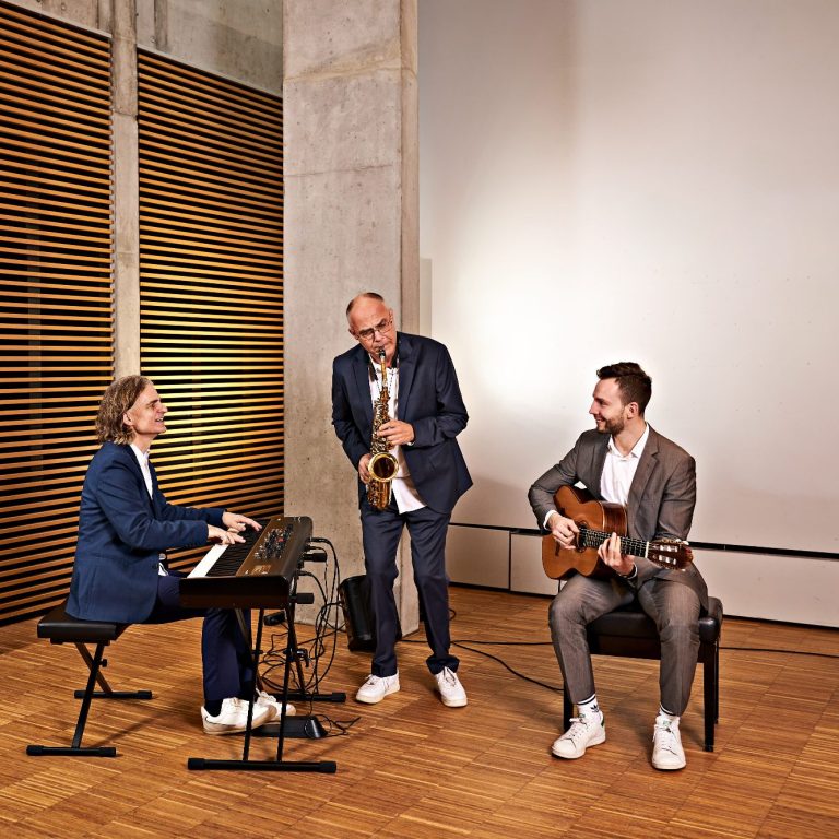 Kleines Ensemble spielt handgemachte Livemusik mit Gitarre, Saxofon und Piano bei einer privaten Festlichkeit.